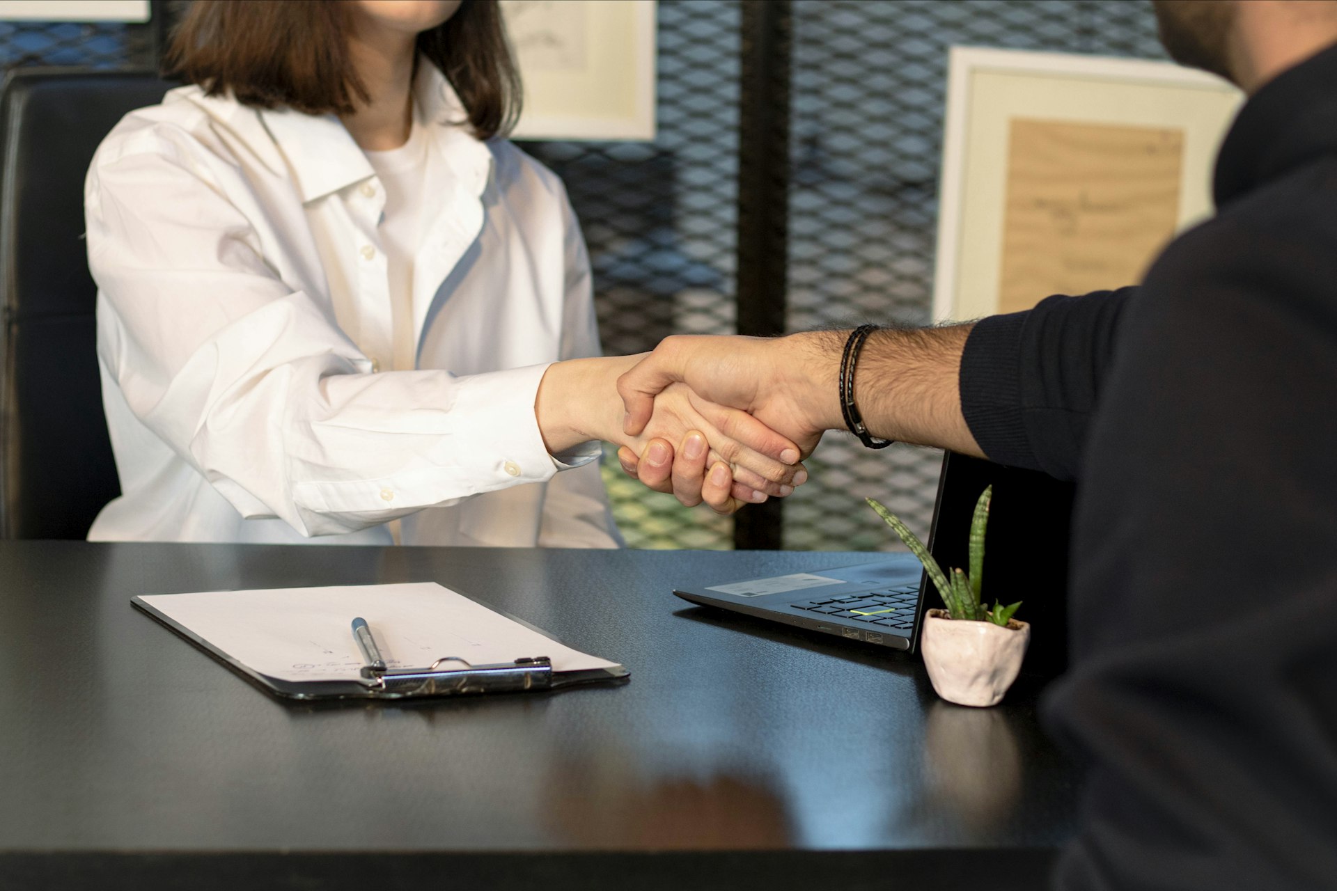 An adviser and a client shaking hands across a desk