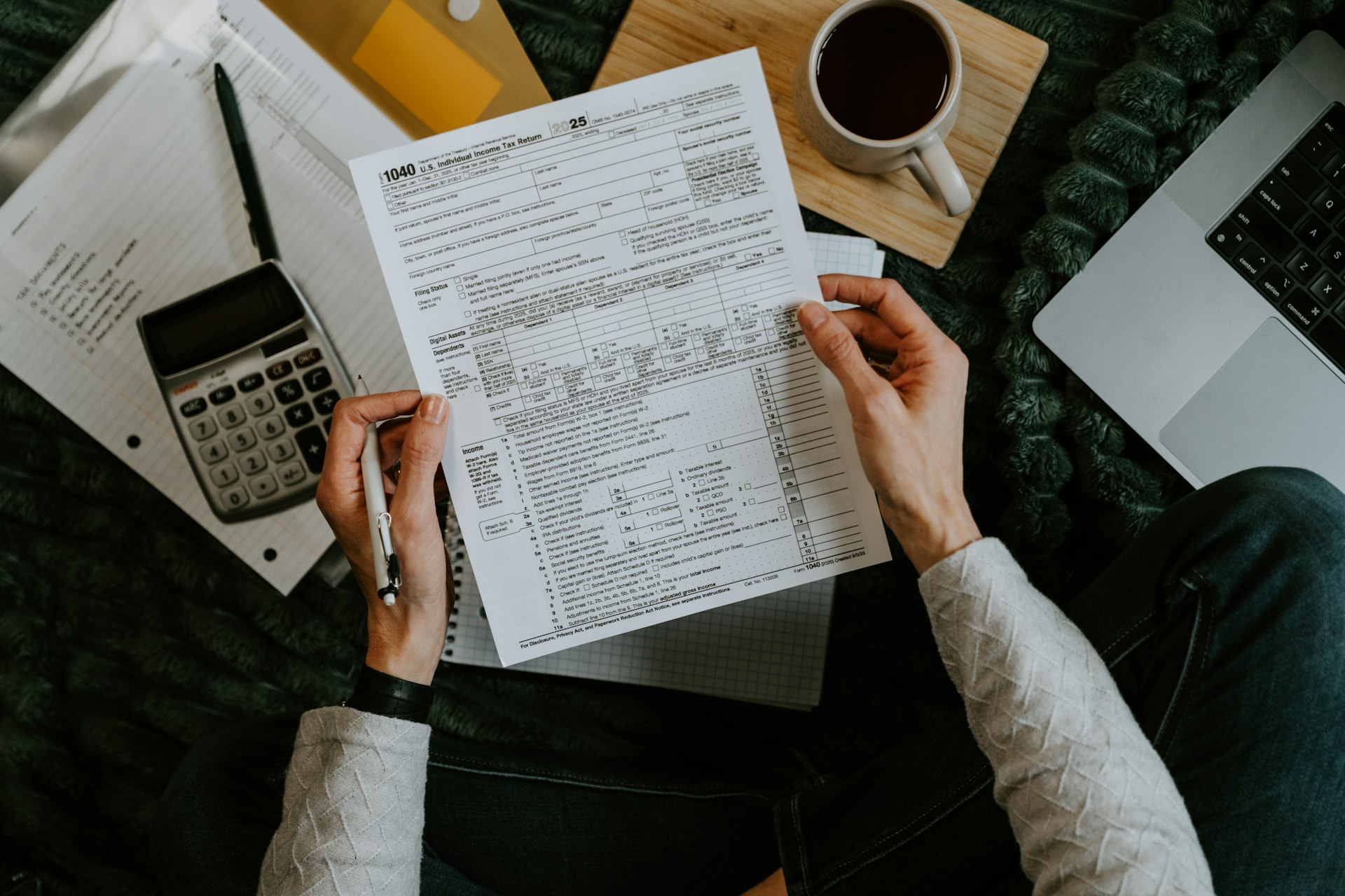 Tax forms, a calculator and a laptop on a desk
